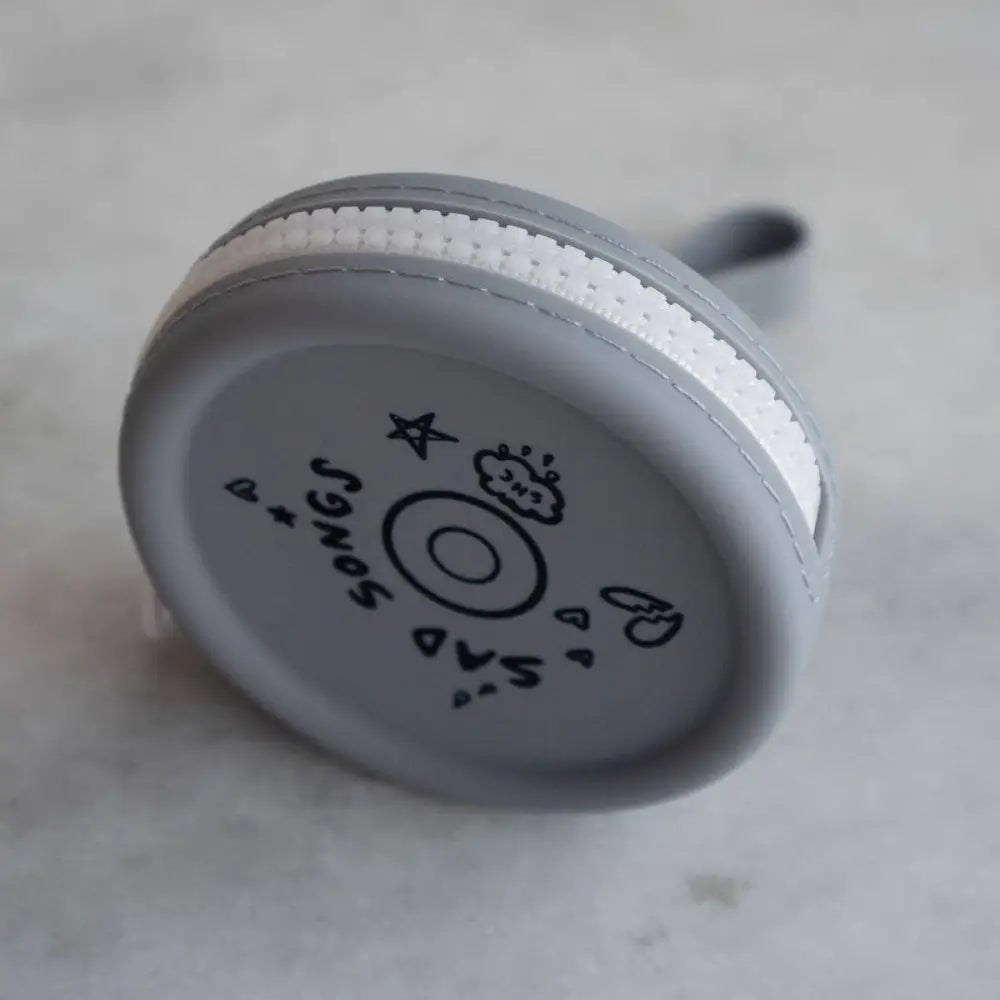 Round zippered pouch with icons and record and text SAD SONGS, grey with black text, white zipper, silicone, top view - PABOOM