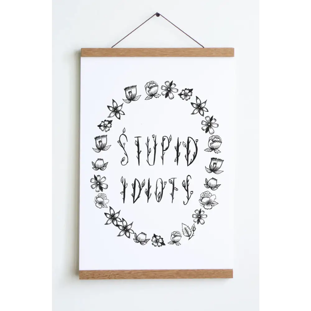 Floral black font saying STUPID IDIOTS surrounded by flower outlines on a white background print - PABOOM