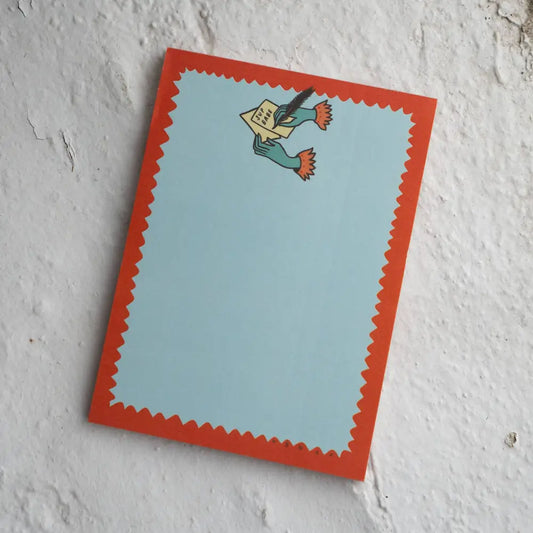 Notepad with a top logo of two hands writing a letter “SUP BABE”. Blue, with red squiggle outline, by Stay Home Club | PABOOM
