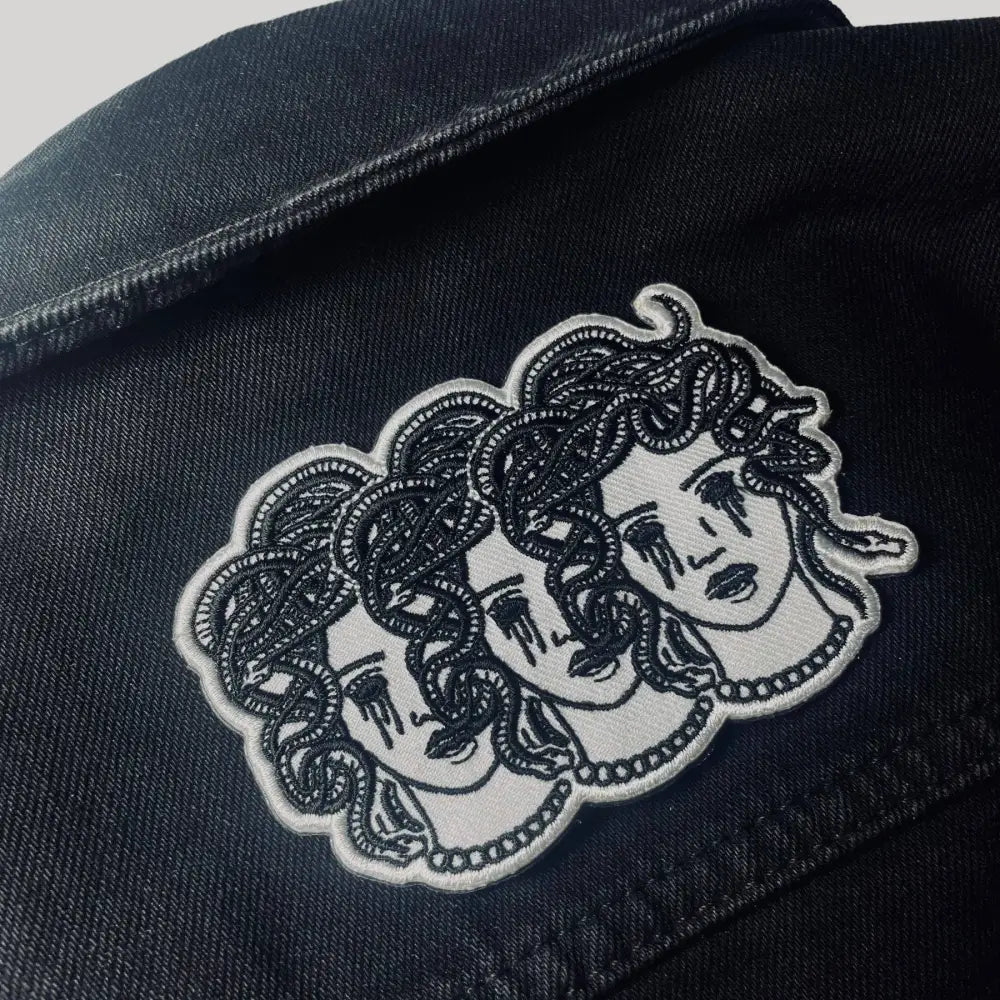 Iron on embroidered patch of three medusa heads with blacked out crying eyes on jacket