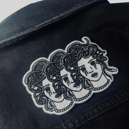 Iron on embroidered patch of three medusa heads with blacked out crying eyes on jacket