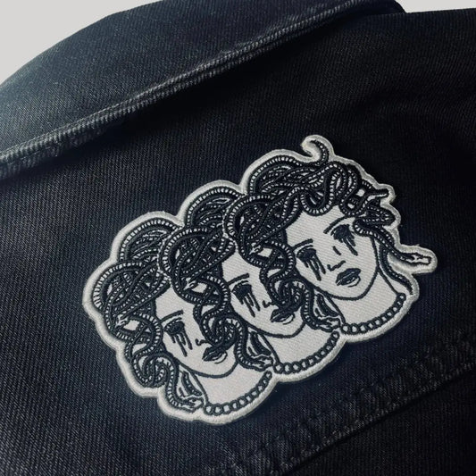 Iron on embroidered patch of three medusa heads with blacked out crying eyes on jacket
