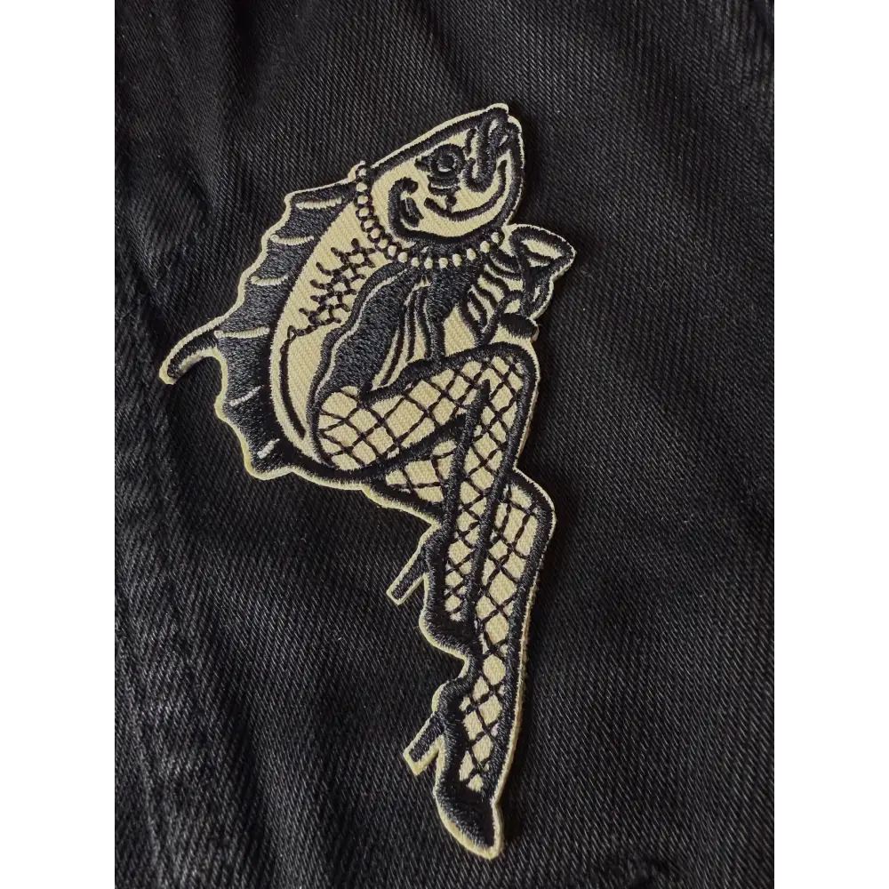 Iron on embroidered patch of a fish with legs wearing fishnets and heels and holding a martini, on fabric