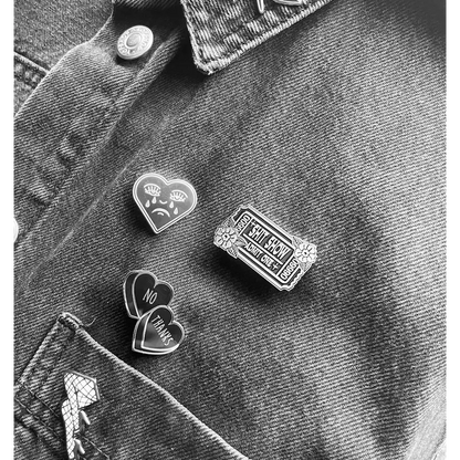 3 enamel pins on grey jean jacket